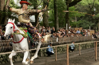 A mounted archer aims at a target from a galloping horse during the Yabusame Shinto ritual at Tsurugaoka Hachimangu
